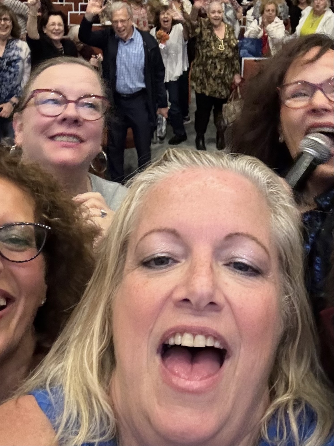 Supersized Comedy performers smiling with a cheering audience behind them